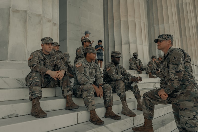 US soldiers in camouflage uniforms sitting on the steps of a marble building