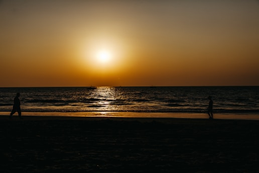 A warm sunset over a serene beach with a family walking along the shore, capturing the essence of peaceful travel moments.