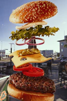 An animated cheeseburger showing layers of meat, cheese, salad, and tomato coming together.
