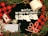 A black t-shirt with 'The Year of the Lockdown 2020' text in white, featuring images of toilet paper rolls and a Santa hat. Surrounding items include a roll of toilet paper, a face mask, candy canes, a red and black checkered Michigan-themed candle, two transparent Christmas ornaments, pine branches, and a rustic rope.