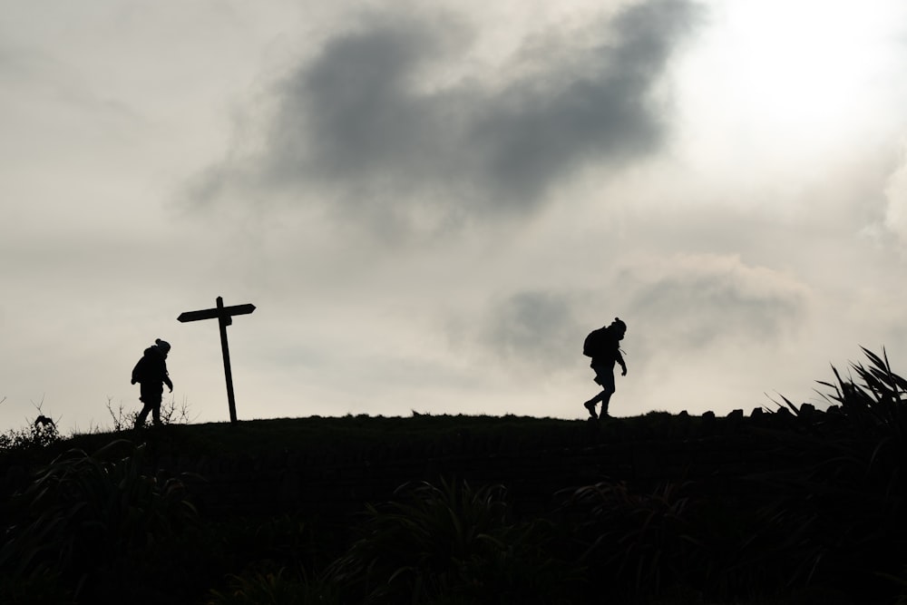 silhouette of person standing on grass field under cloudy sky during daytime