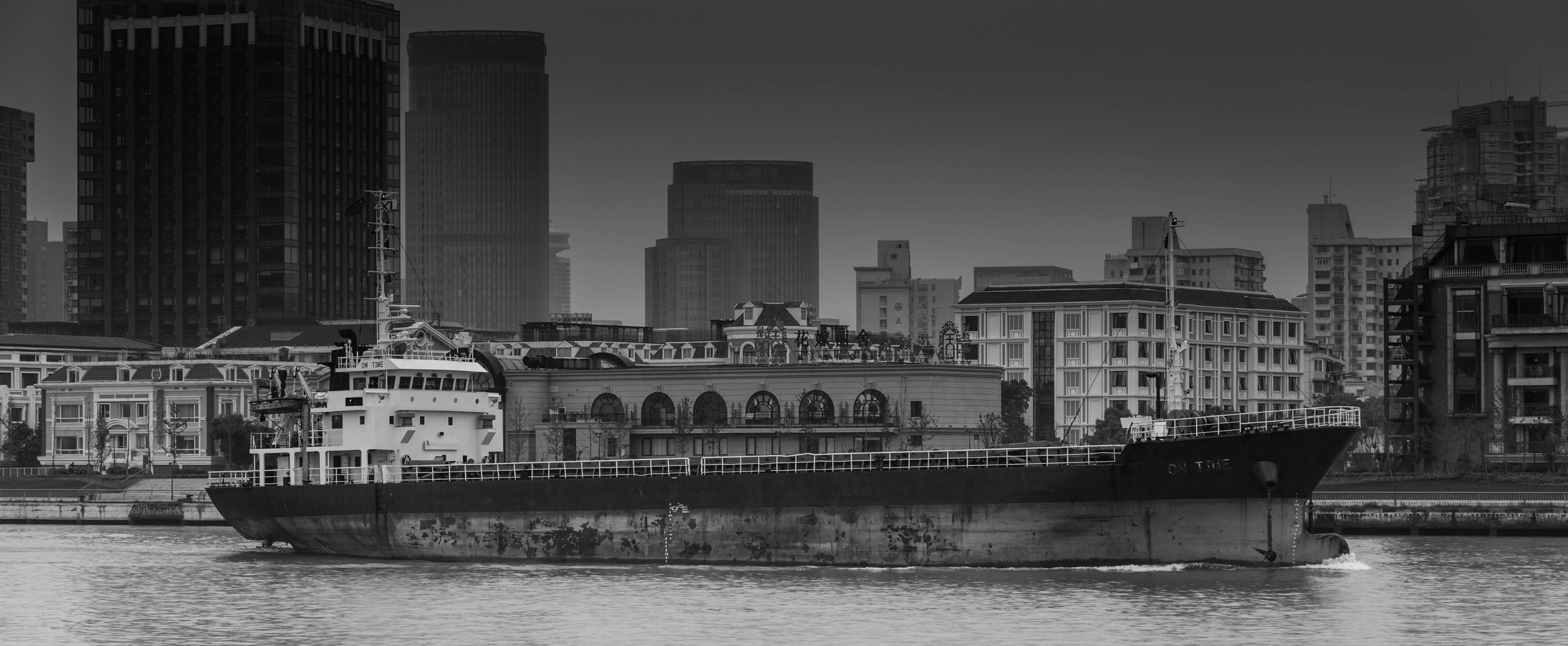 grayscale photo of city buildings near body of water