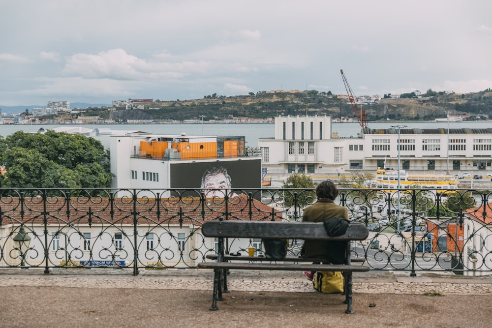 man and woman sitting on bench near body of water during daytime