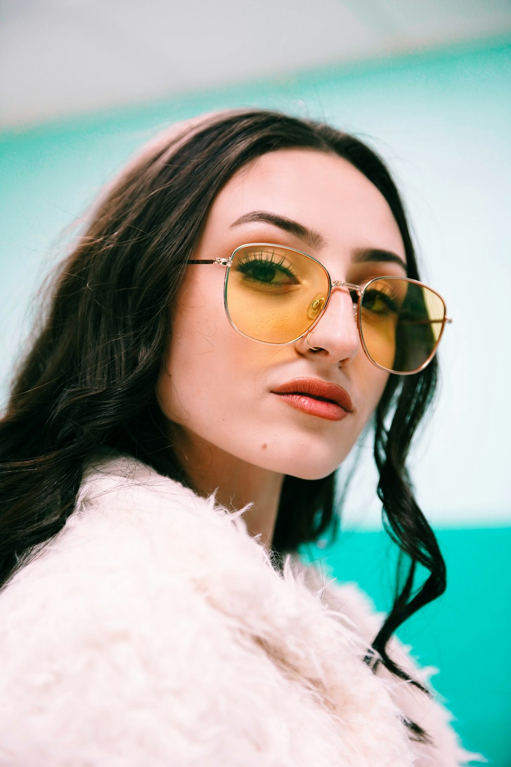 woman in white fur coat wearing gold framed aviator sunglasses