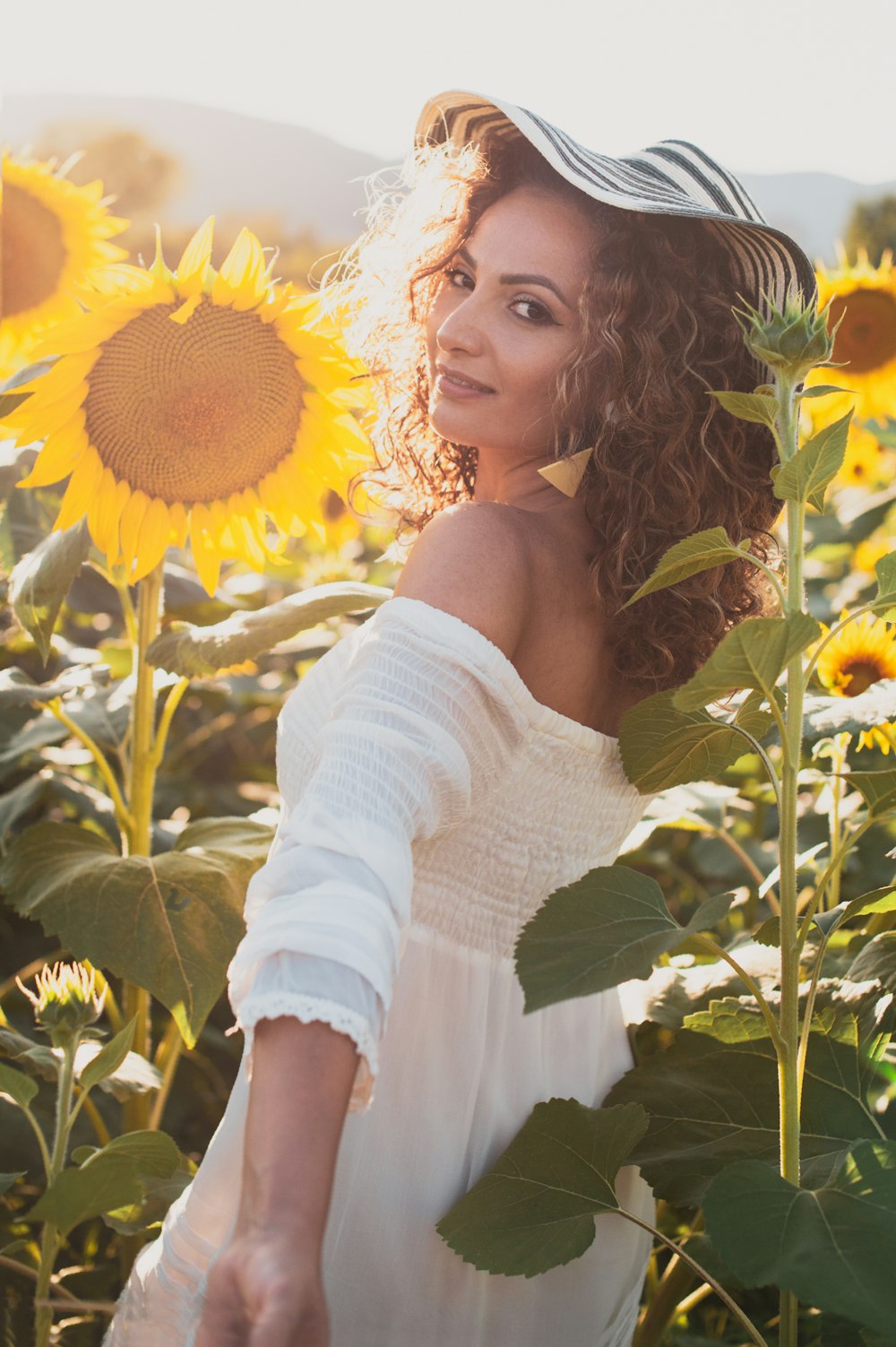 woman in white off shoulder long sleeve shirt holding sunflower