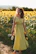 Happy woman holding a bottle of Gosattuu outdoors with green fields behind.