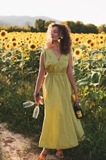 woman in yellow sleeveless dress holding white and black hair brush standing on yellow flower field