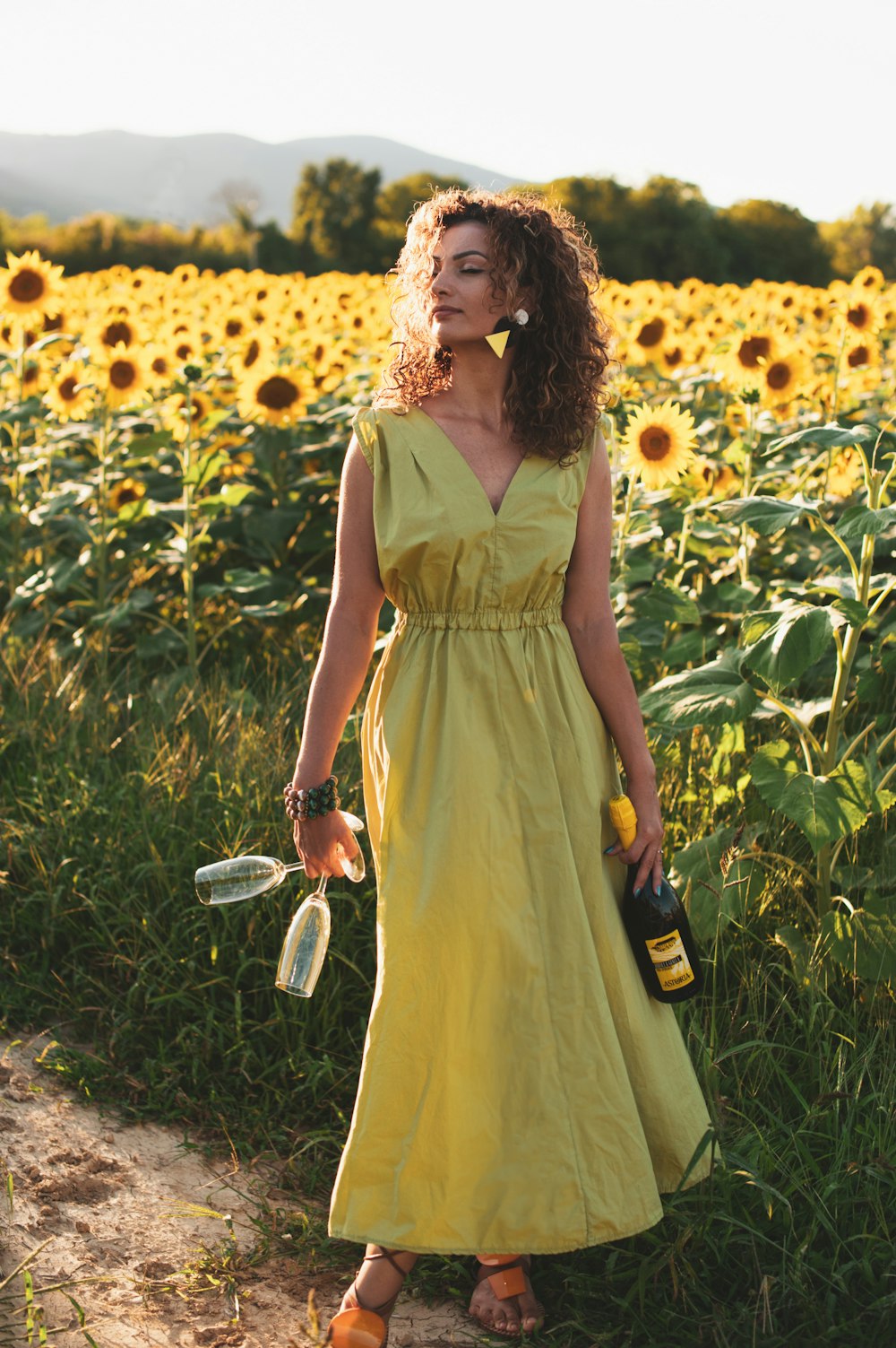 woman in yellow sleeveless dress holding white and black hair brush standing on yellow flower field