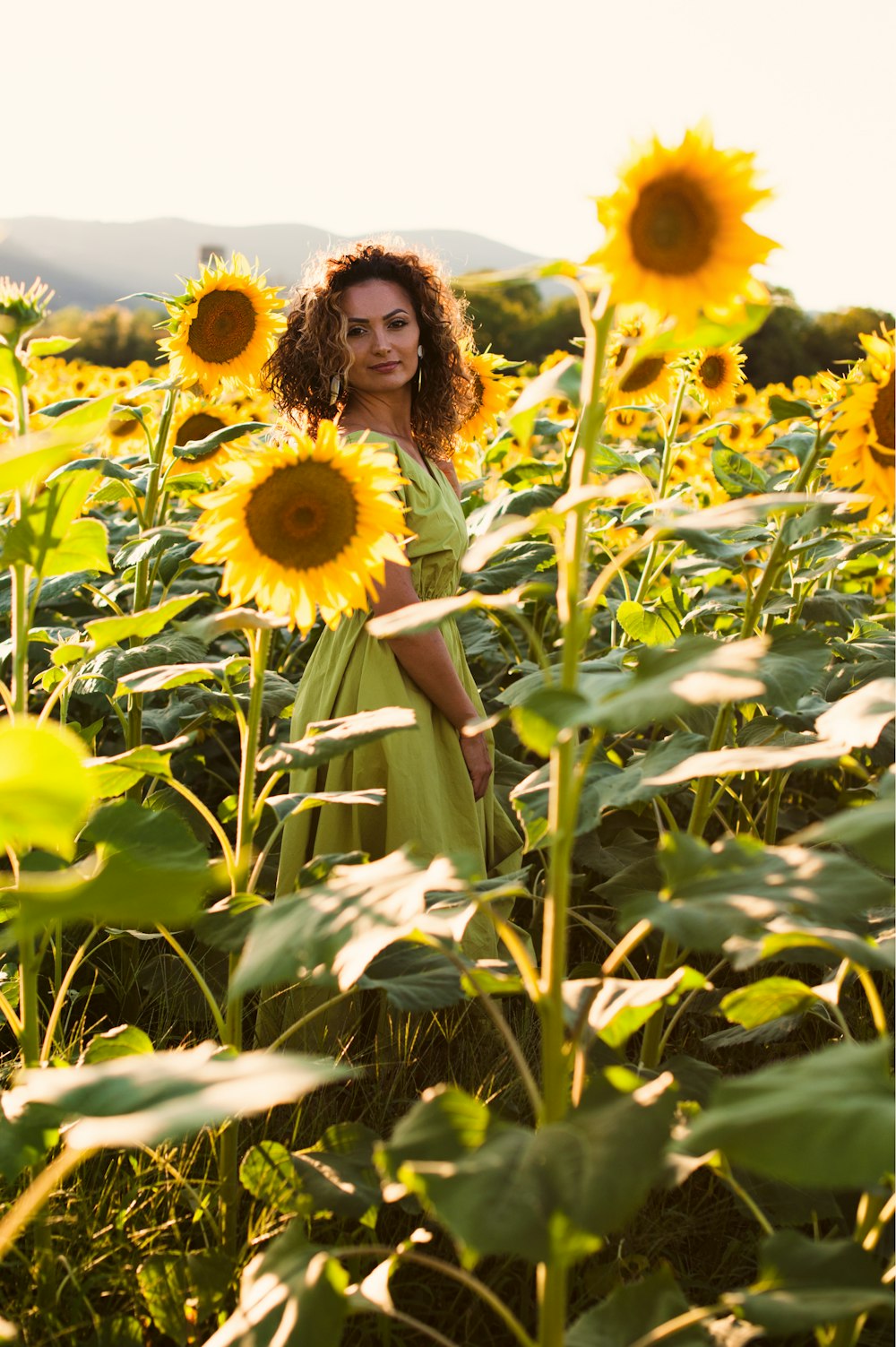 woman in white dress standing on sunflower field during daytime