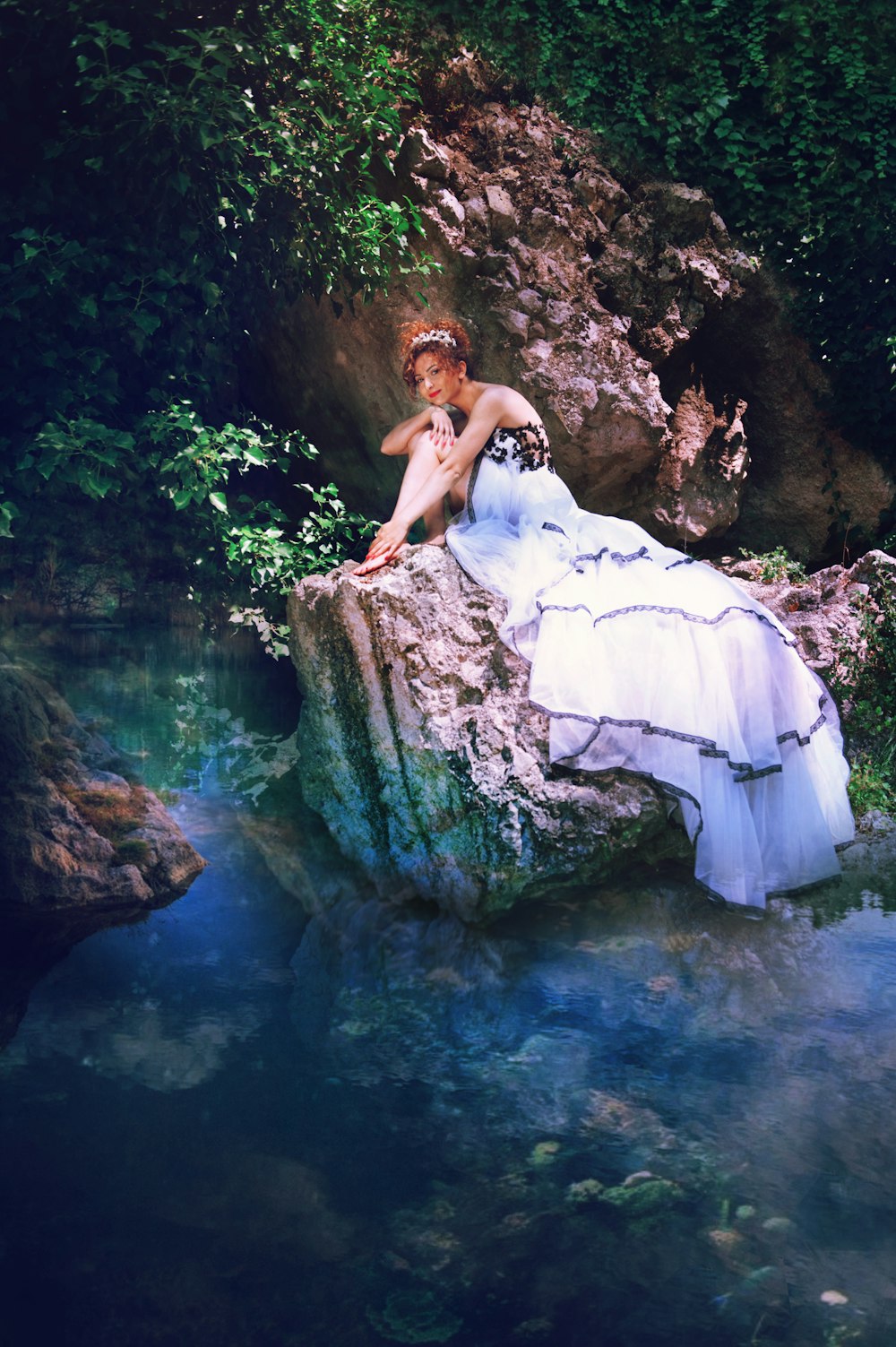 woman in white dress sitting on rock in water