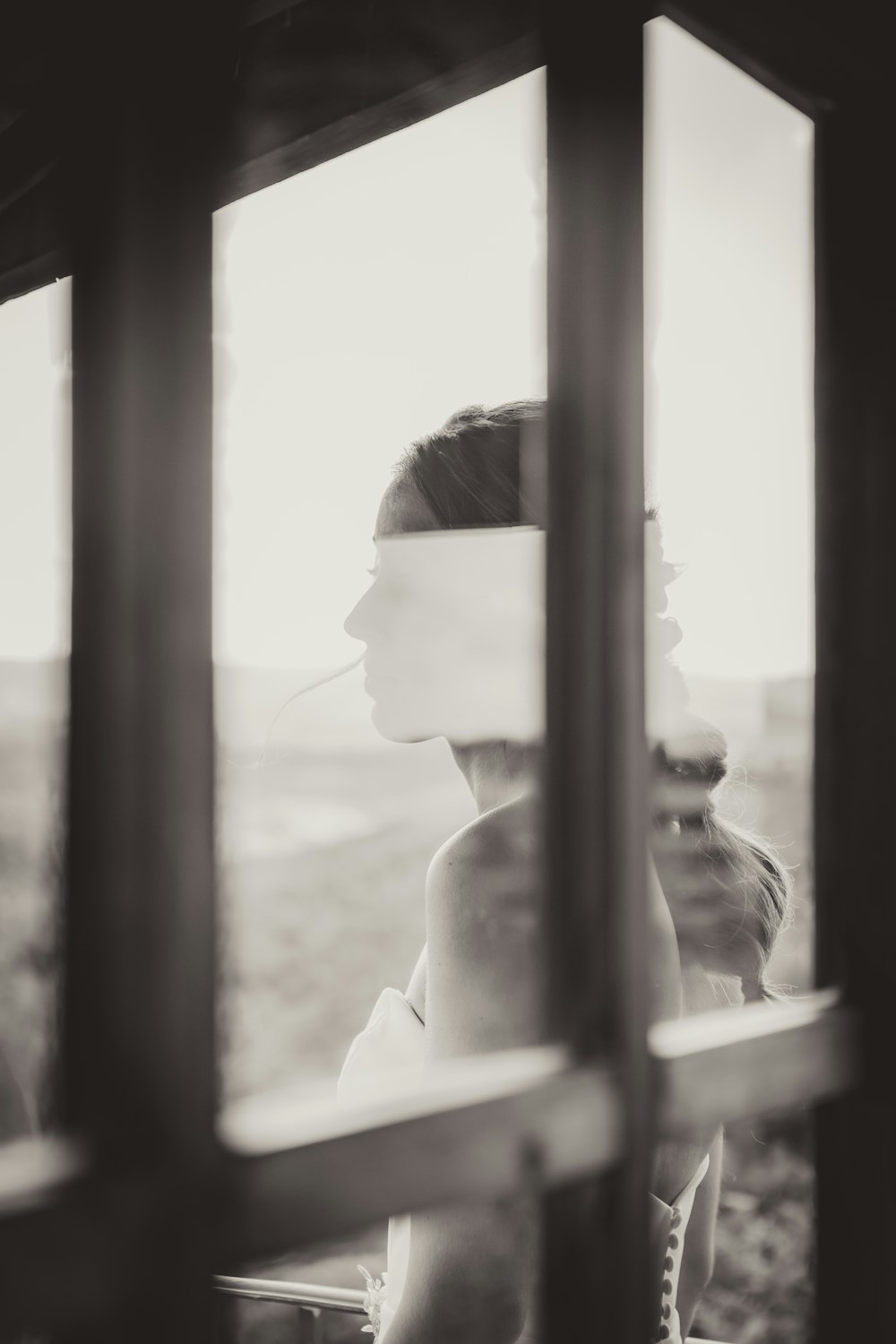 Mujer con camisa blanca mirando por la ventana