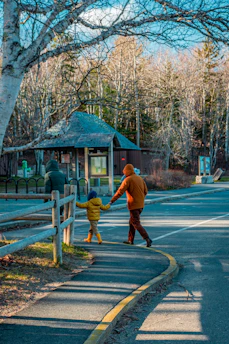 A couple wearing matching scarves walking hand-in-hand through a crisp autumn park.