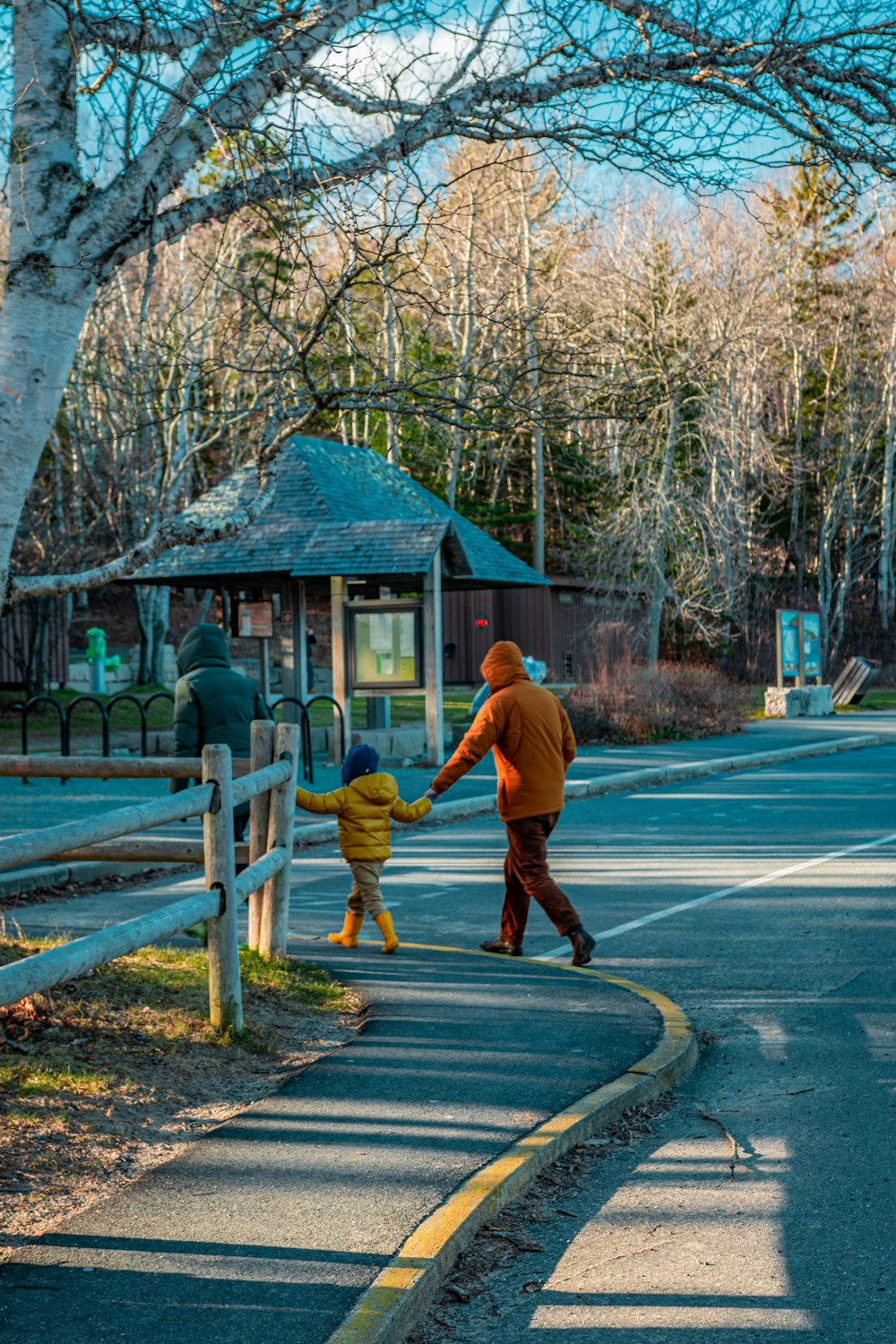 man in orange jacket and brown pants walking on road during daytime