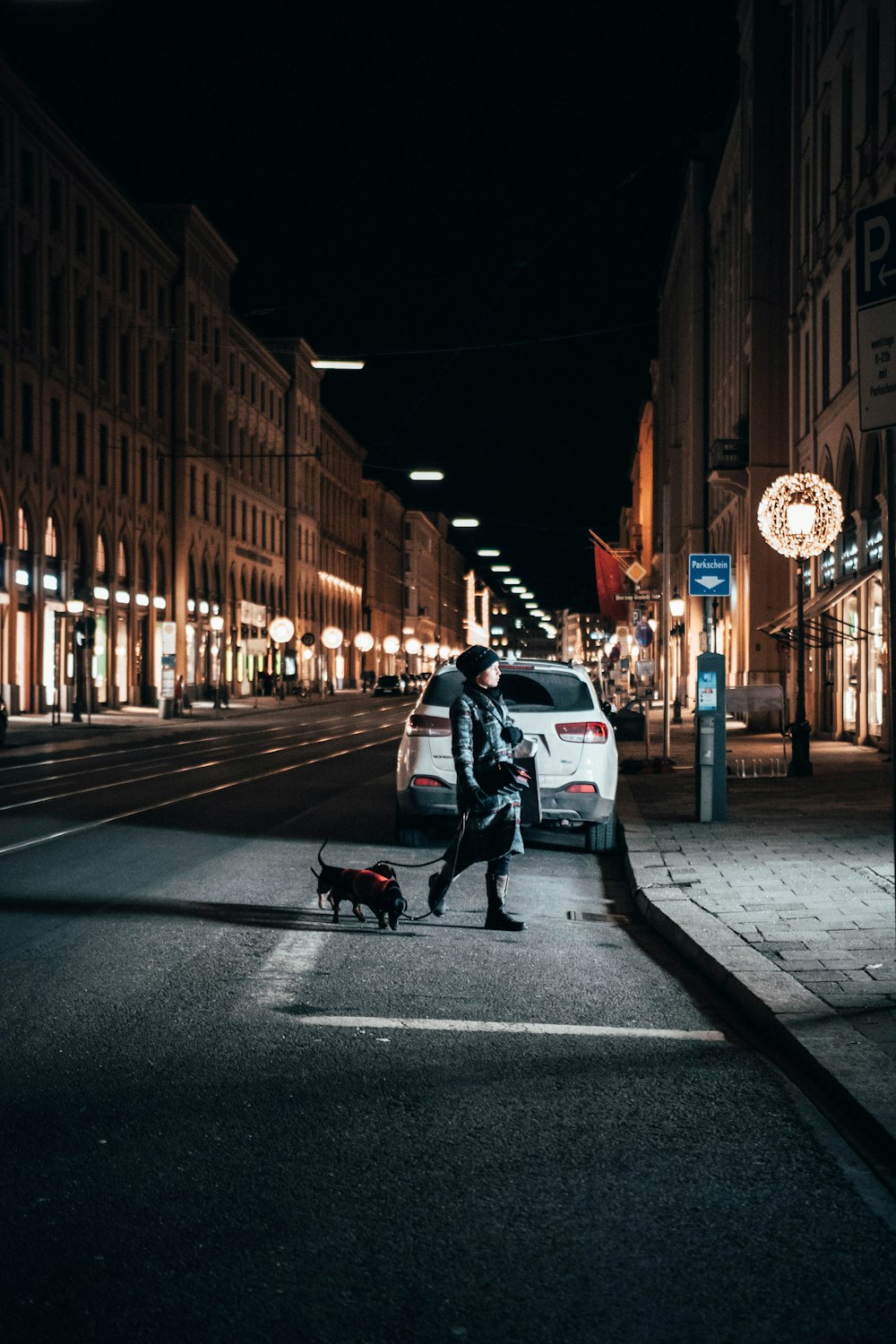 man in black jacket and black pants walking on sidewalk during night time