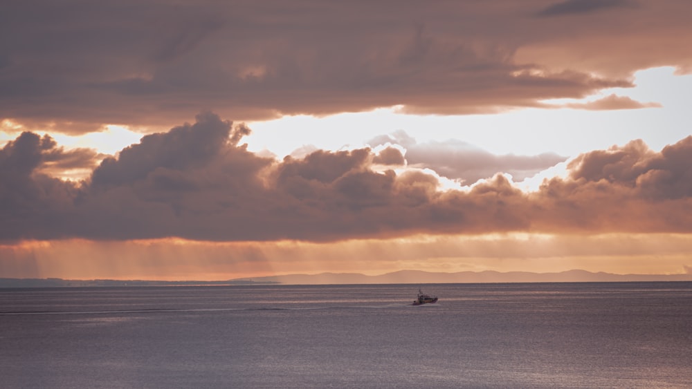 boat on sea under cloudy sky during sunset