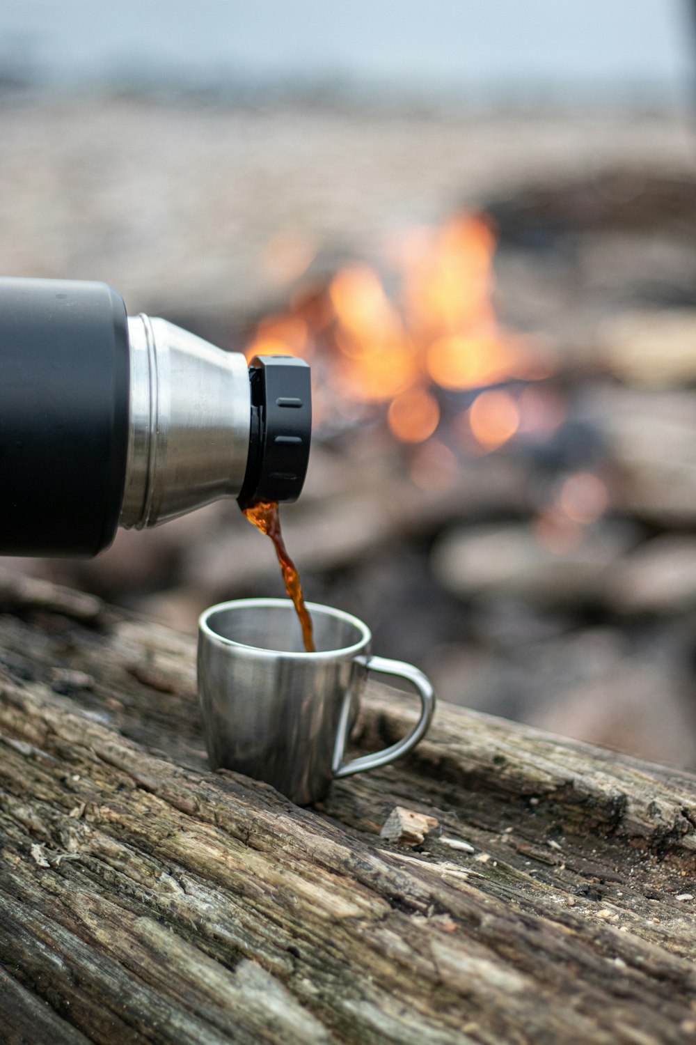 caneca de café prateada e preta na mesa de madeira marrom