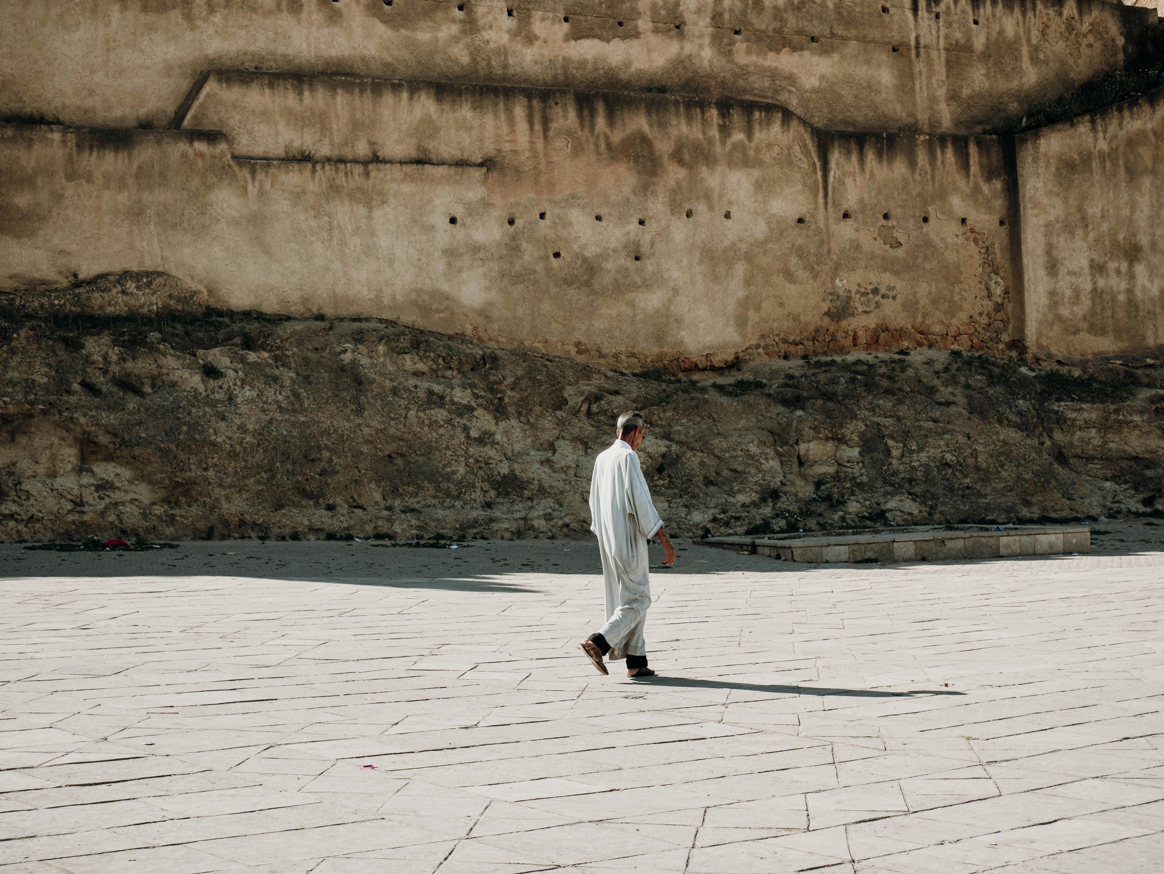 man in white thobe standing on gray concrete floor during daytime