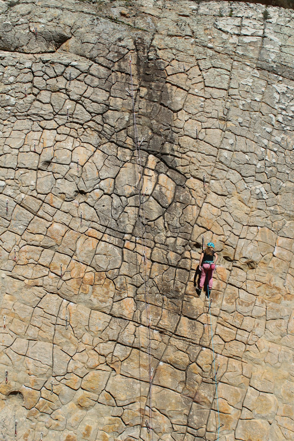 woman in blue jacket climbing on brown rocky mountain during daytime