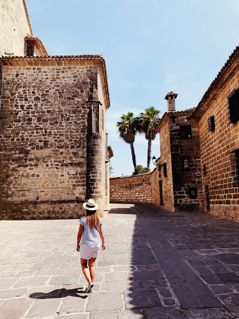 woman in white and black stripe dress walking on gray concrete pathway during daytime