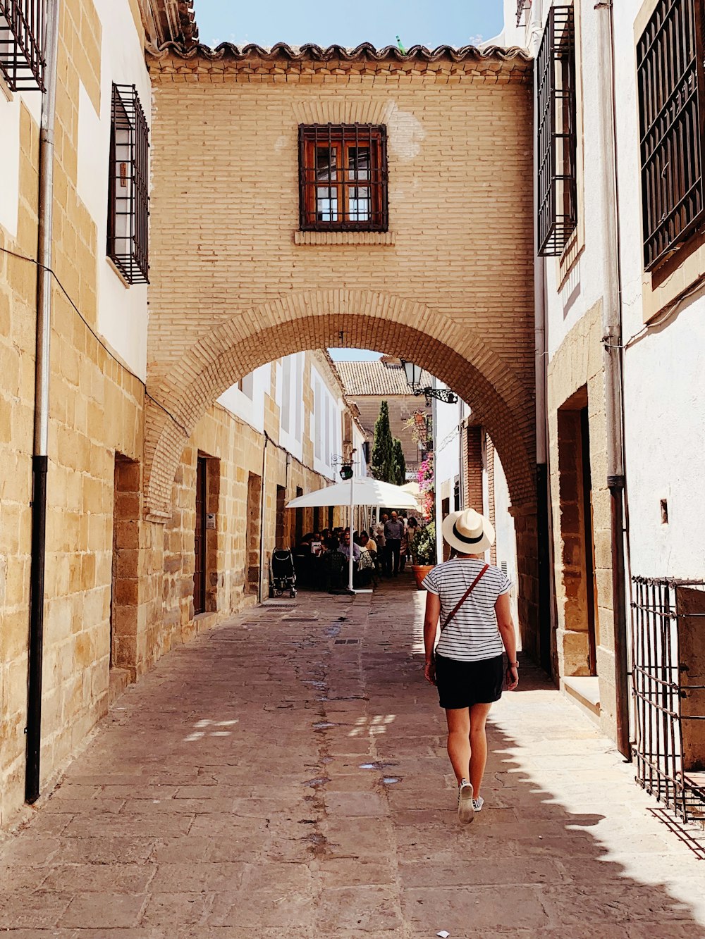 woman in white and black stripe shirt and black skirt walking on pathway