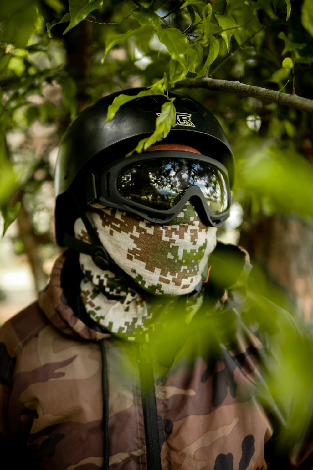 Homme en veste de camouflage verte et marron portant un casque noir