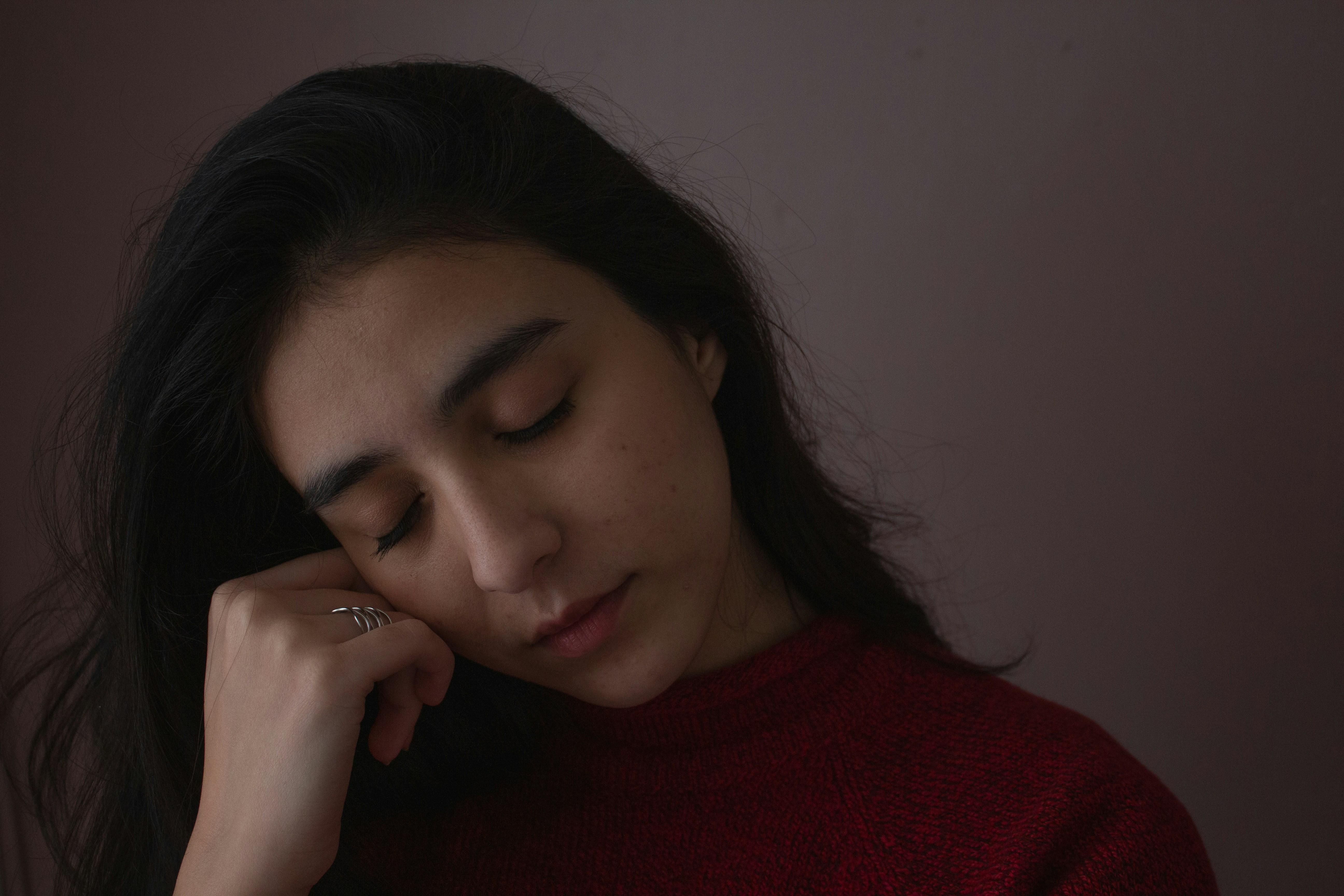 a woman in a red sweater holding her hand to her face