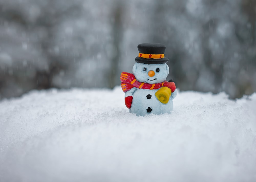 赤いスカーフと白い帽子の陶器の置物の雪だるま