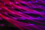 Bright neon colors creating a dynamic effect with blurred lines. Letters are scattered across the image in a distorted and artistic manner.