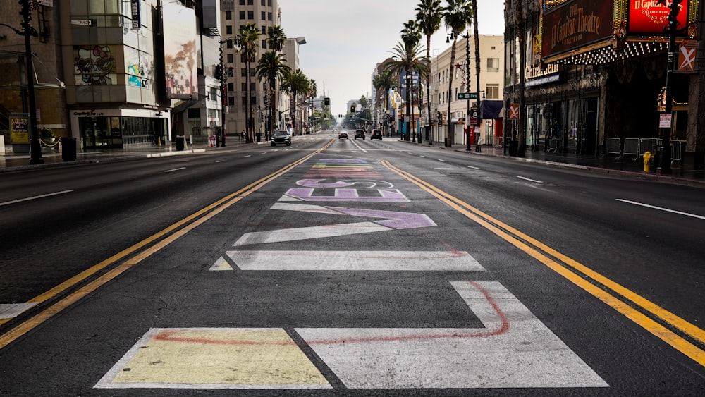 gray concrete road between palm trees during daytime