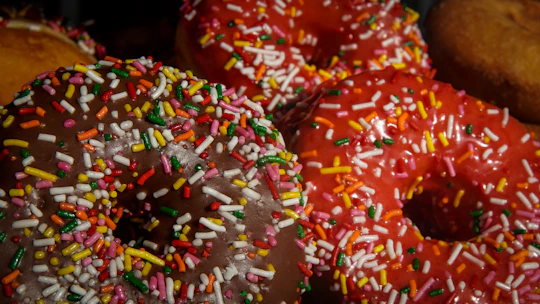 Close-up of colorful vegan donuts with vibrant glazes and toppings on a rustic wooden board.