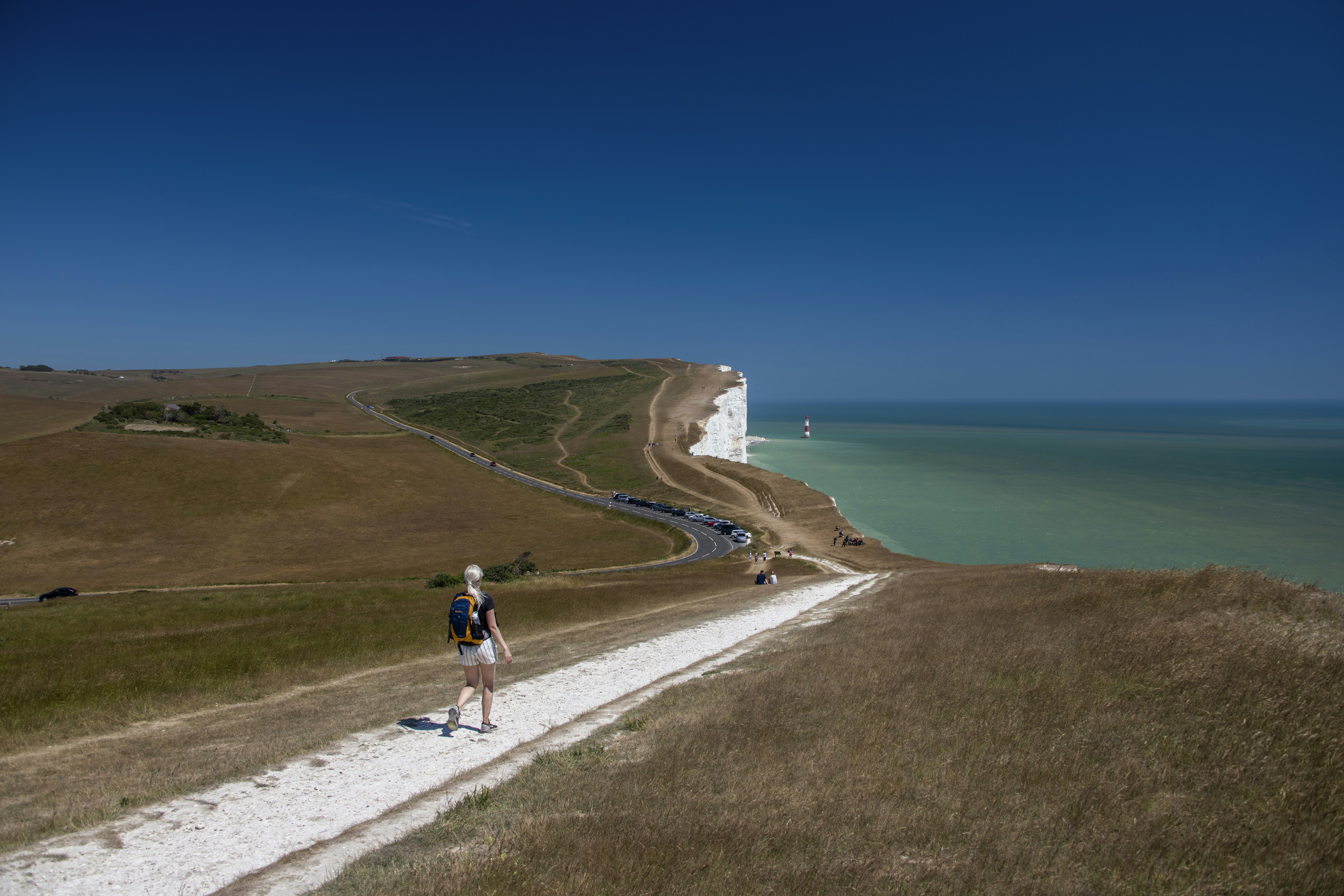 昼間、海辺の道路を歩く2人