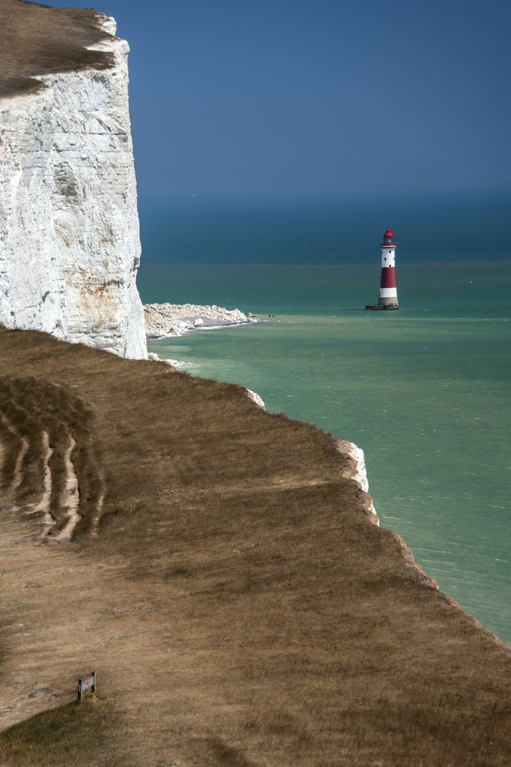 white and red lighthouse near body of water during daytime