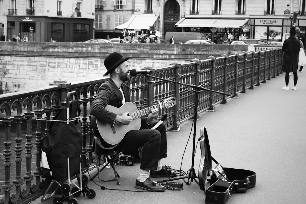 grayscale photo of man playing guitar