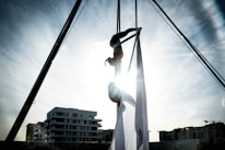 Coach demonstrating aerial silks techniques in a bright studio.