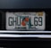 A Florida license plate with the numbers and letters 'GHUL69'. It features the outline of the state and an orange graphic with blossoms. The text 'SUNSHINE STATE' is displayed at the bottom with the website 'MYFLORIDA.COM' at the top. There is a yellow sticker in the upper right corner indicating an expiration date of 06-19.