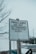 A weathered sign stands prominently, warning visitors that parklands are not to be treated as litterboxes for the sake of children. The bottom of the sign reminds readers to clean up after their pets. It is mounted on a wooden post and set against a background of bare trees and a snowy landscape, possibly in an urban setting.