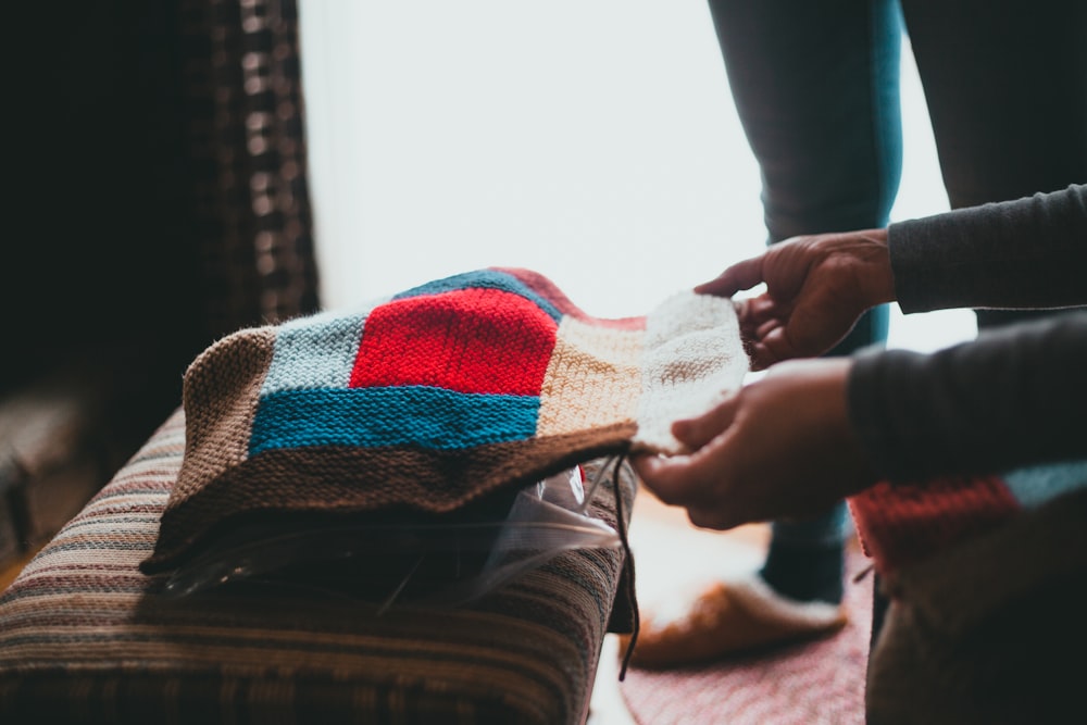 person holding white blue and red plaid textile