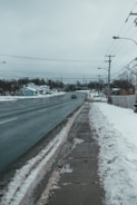 A technician installing weather sensors on a snowy roadside to monitor conditions affecting vehicle safety