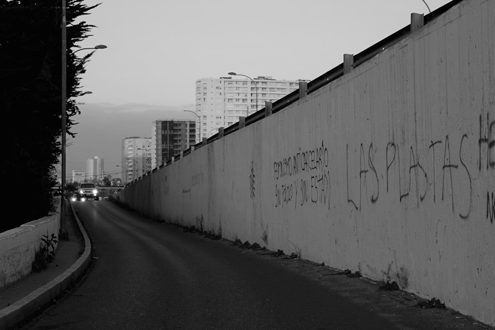 grayscale photo of concrete wall with graffiti