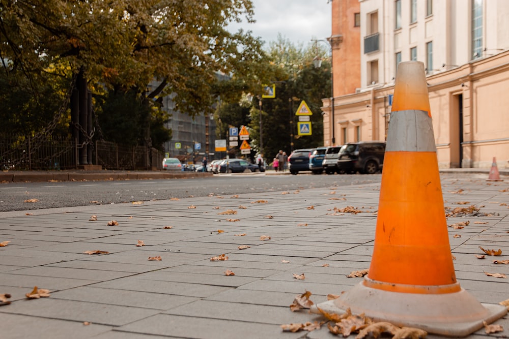 orange and white traffic cone on gray concrete pavement