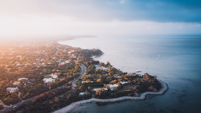 A wide-angle view of a coastal village at golden hour, with a compass icon subtly overlaid.