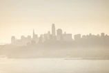 City skyline at night with subtle fog and muted lights creating a cinematic mood.