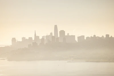 City skyline at night with subtle fog and muted lights creating a cinematic mood.