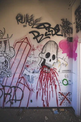 A wall painted with bold black and yellow spray patterns, accented by subtle floating skull designs.
