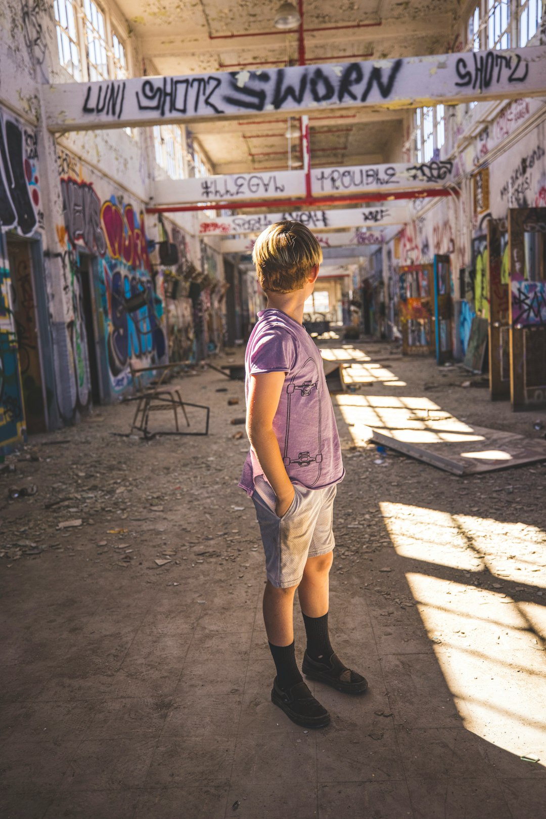 girl in pink t-shirt and blue denim shorts standing on sidewalk during daytime