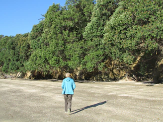 woman in blue long sleeve shirt standing on gray asphalt road during daytime