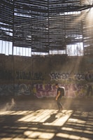 A survivor scavenging loot inside a dilapidated building with sunlight filtering through broken windows
