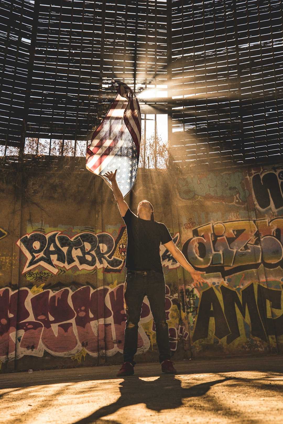 woman in white and red floral sleeveless shirt and black pants standing in front of graffiti