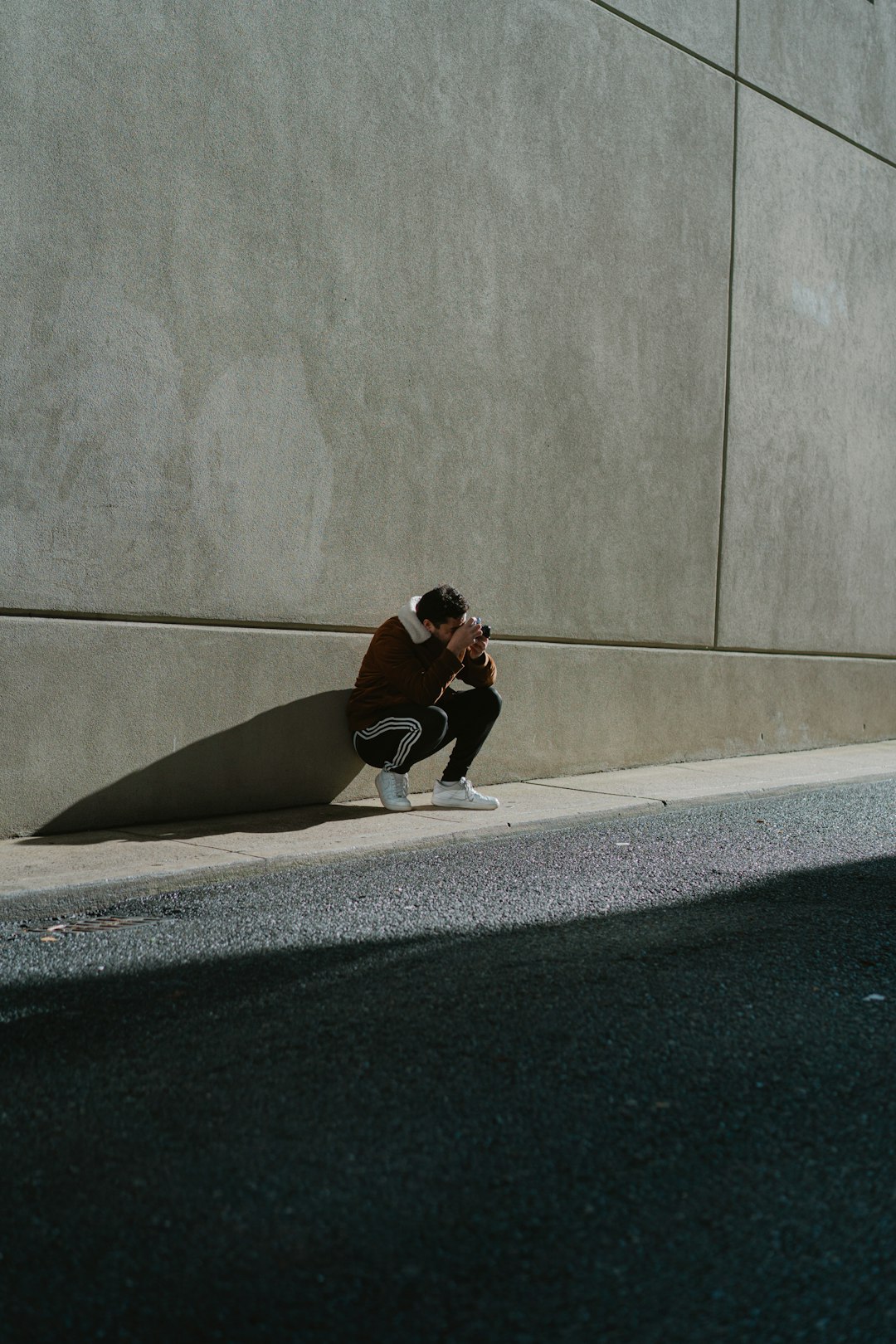 woman in black long sleeve shirt and black pants sitting on gray concrete floor