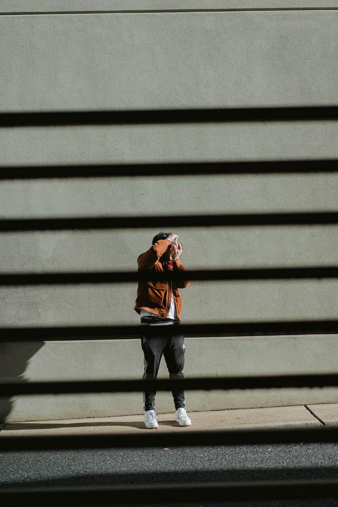 woman in brown jacket and black pants standing on gray concrete stairs